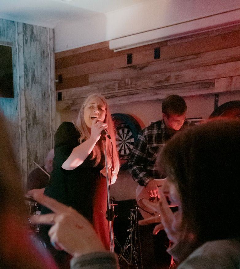 Kylie, lead vocalist of On The Rocks, singing into the mic mid-song at a live pub gig